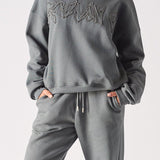 A woman wearing a stylish ladies oversized grey sweatshirt with tonal embroidery.