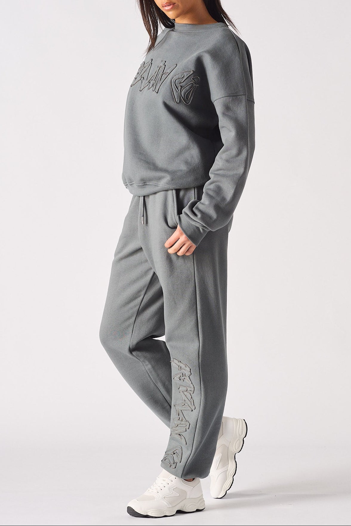 Side profile of a model posing in the relaxed ladies oversized grey sweatshirt.