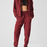 Back view of a model in burgundy ladies red joggers and a matching hoodie.
