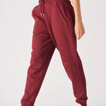 Stylish side profile of a woman wearing relaxed fit ladies red joggers.
