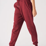 Stylish side profile of a woman wearing relaxed fit ladies red joggers.