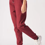 Side view of a model walking while wearing comfortable ladies red joggers.