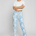 Model leaning casually against a wall wearing ladies retro swirl light blue denim with a straight leg.