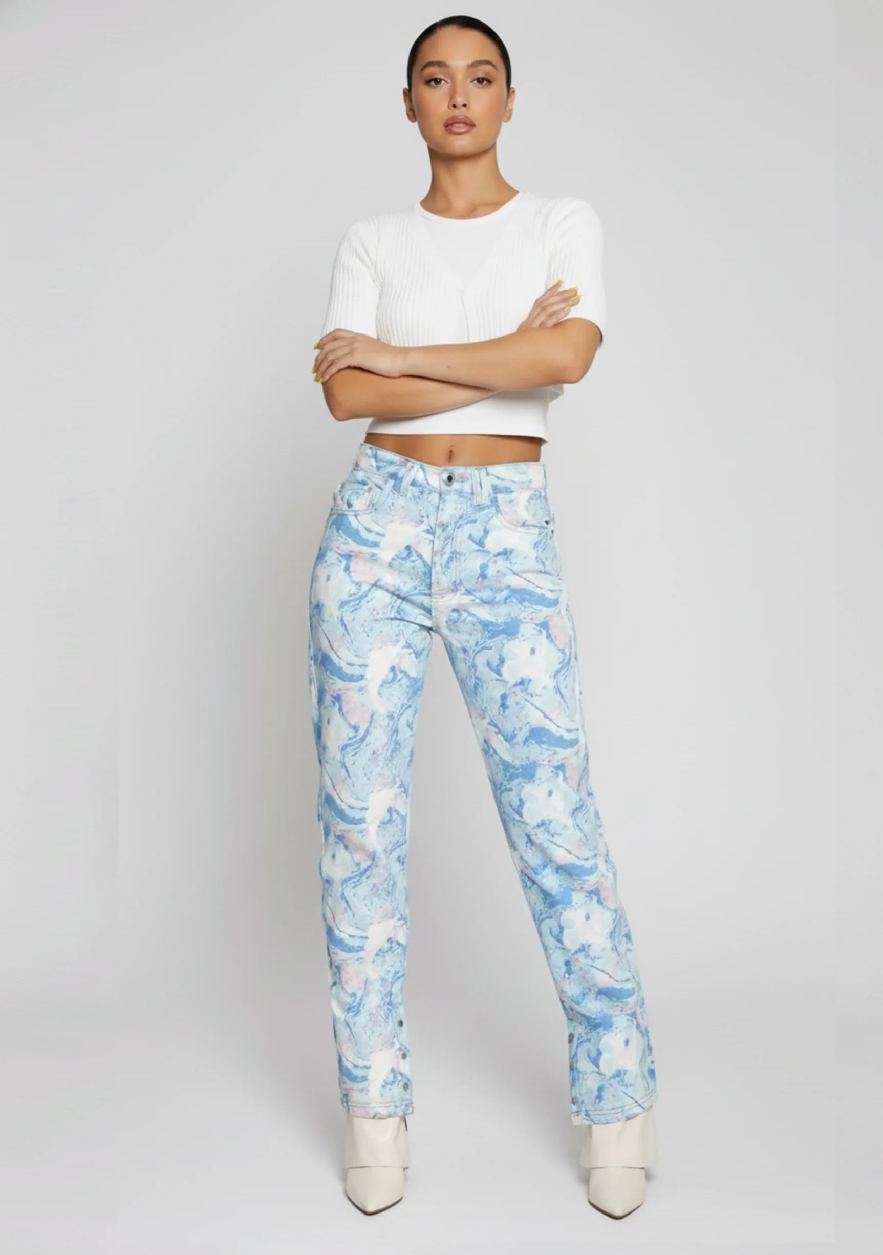 Model leaning casually against a wall wearing ladies retro swirl light blue denim with a straight leg.