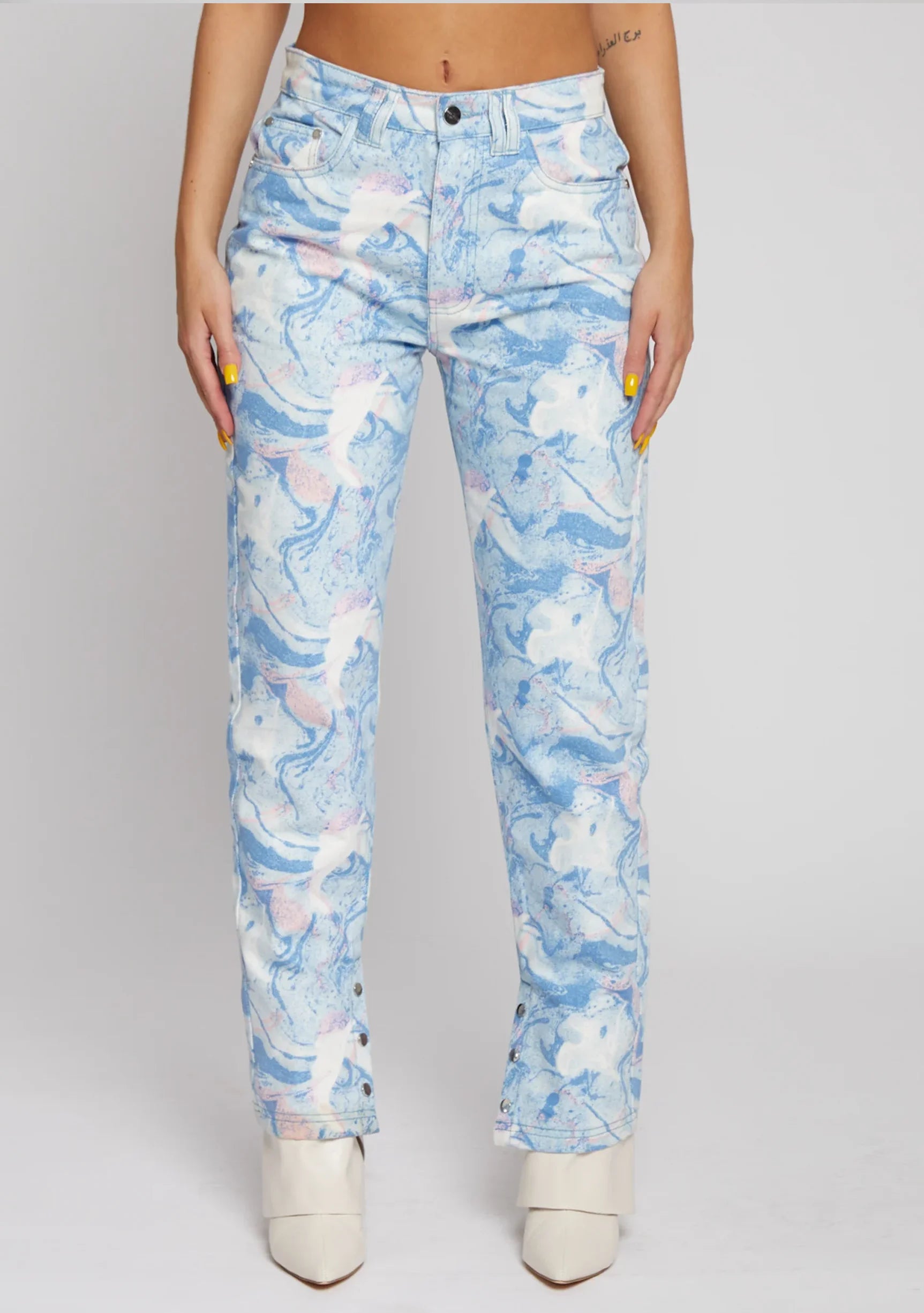 Close up of the front legs and split hem detail on light blue abstract wash denim pants.