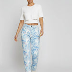 Close up of the front waist and button closure on high-rise light blue acid marble jeans.