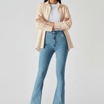Model with arms crossed wearing fitted light blue bootcut jeans