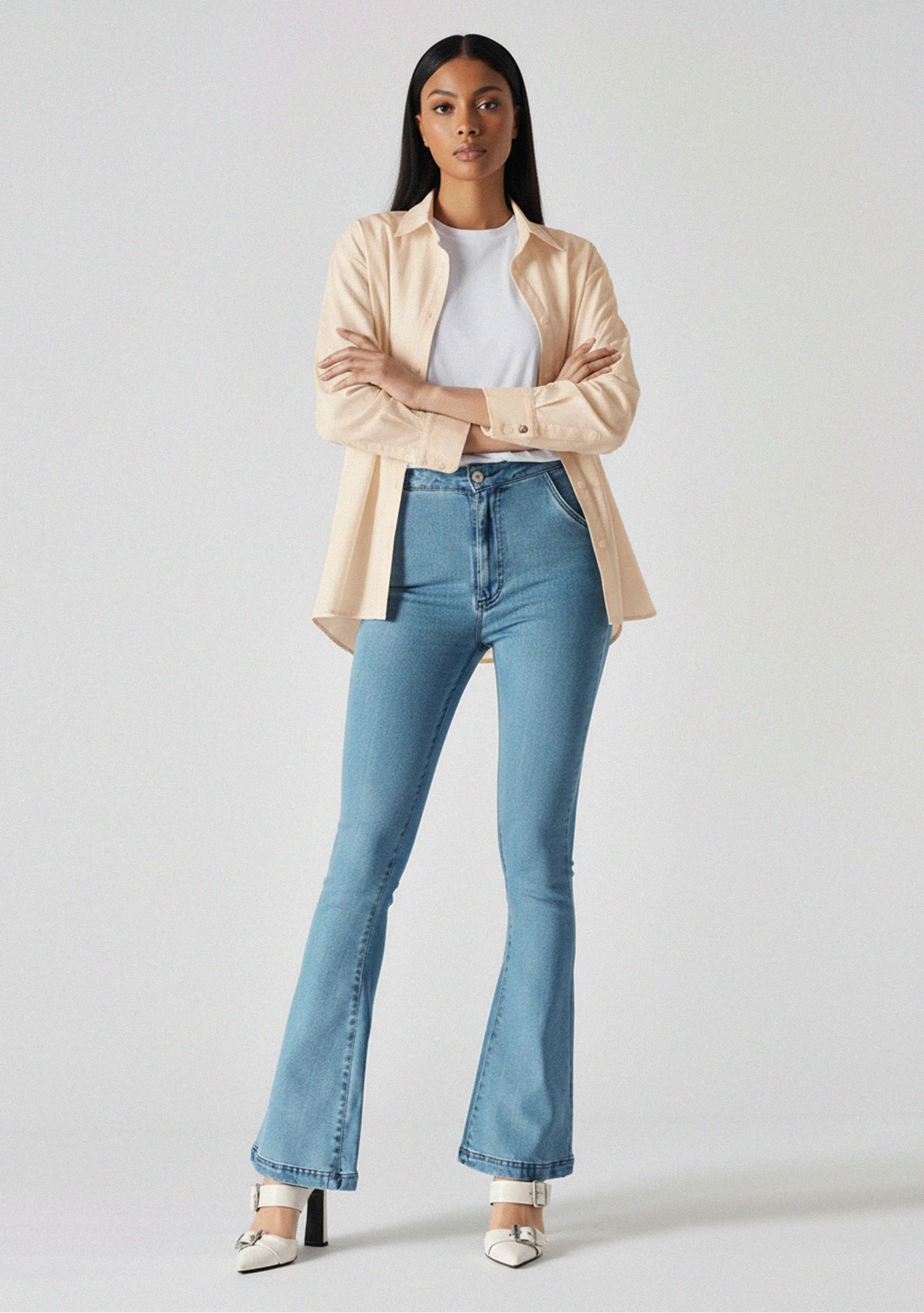 Model with arms crossed wearing fitted light blue bootcut jeans