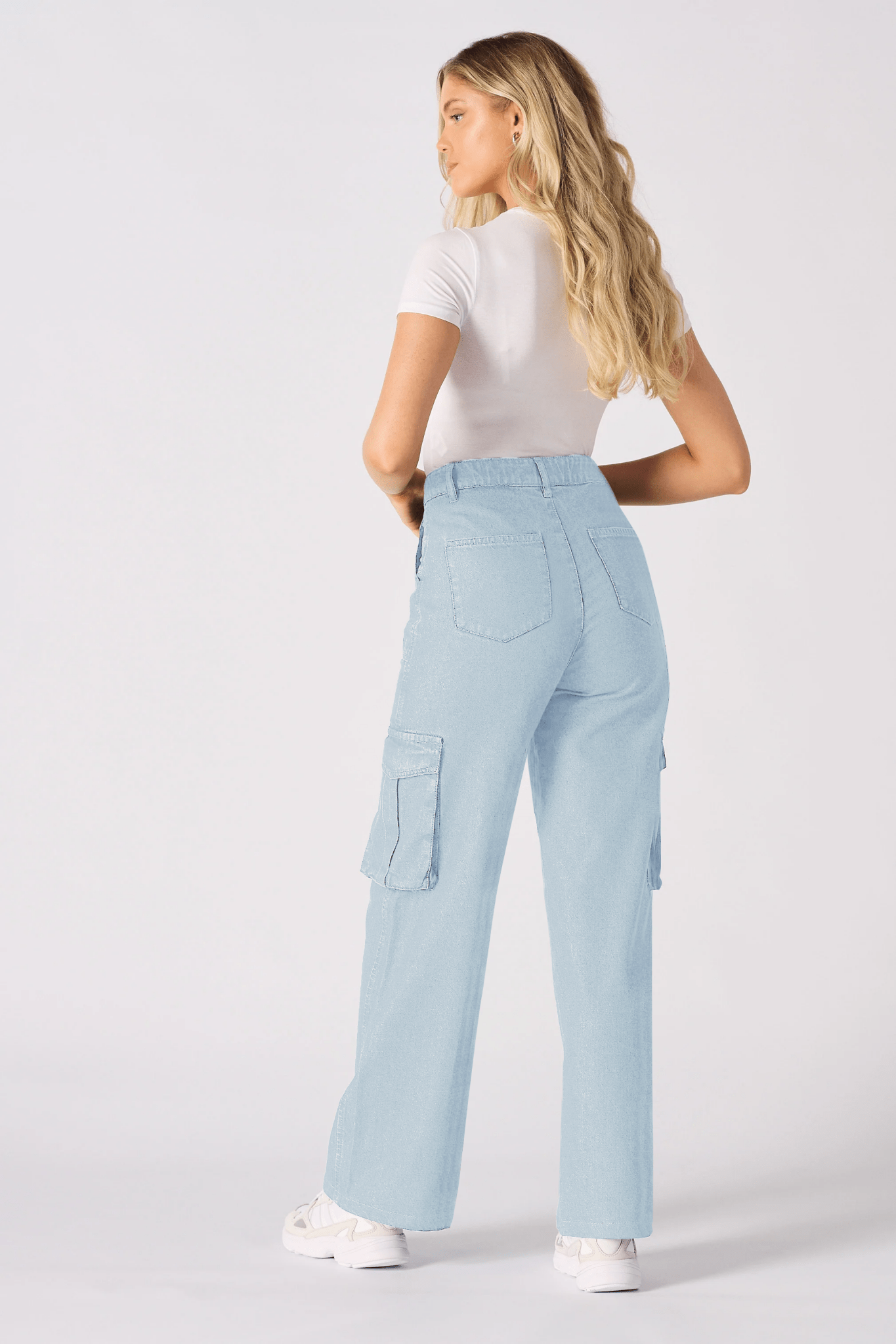 The back view of a woman wearing high-waisted light blue cargo jeans for women showing a flattering fit.