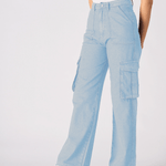 A woman posing at an angle to show the style and comfort of the light blue cargo jeans for women.