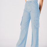 A woman posing at an angle to show the style and comfort of the light blue cargo jeans for women.