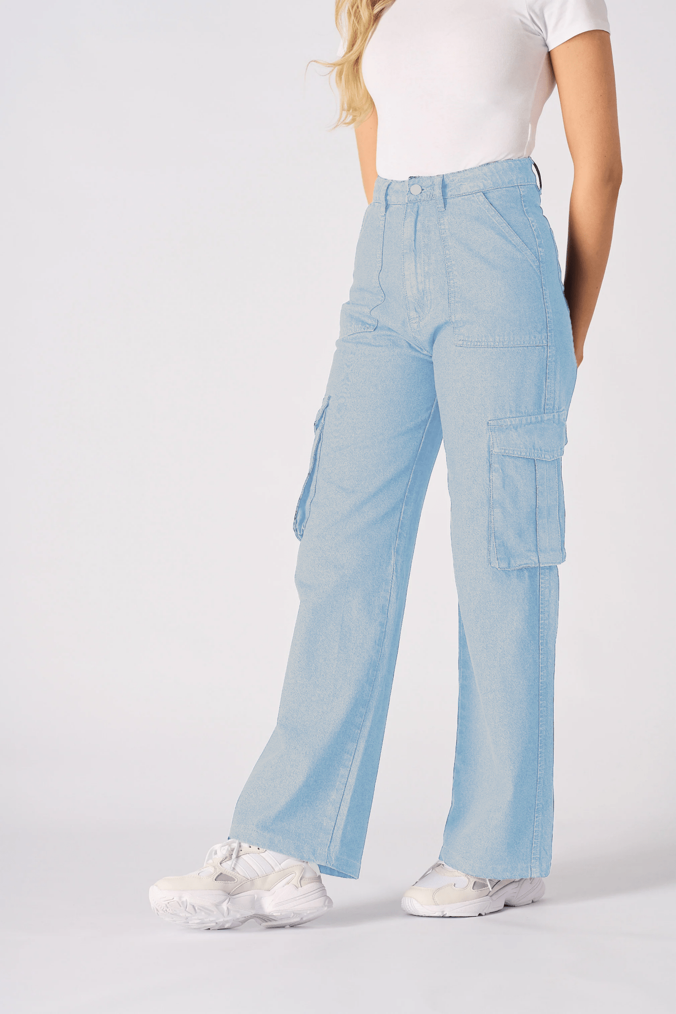 A woman posing at an angle to show the style and comfort of the light blue cargo jeans for women.