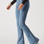 Person wearing light blue flared jeans and black top on a white background