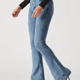 Person wearing light blue flared jeans and black top on a white background