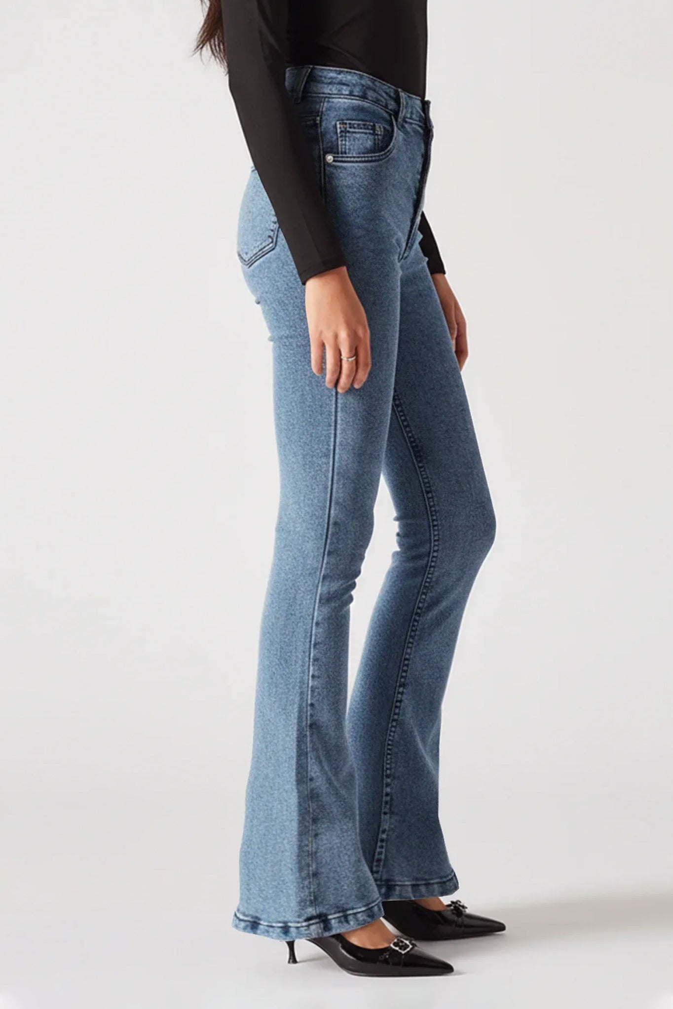 Person wearing light blue flared jeans on a white background