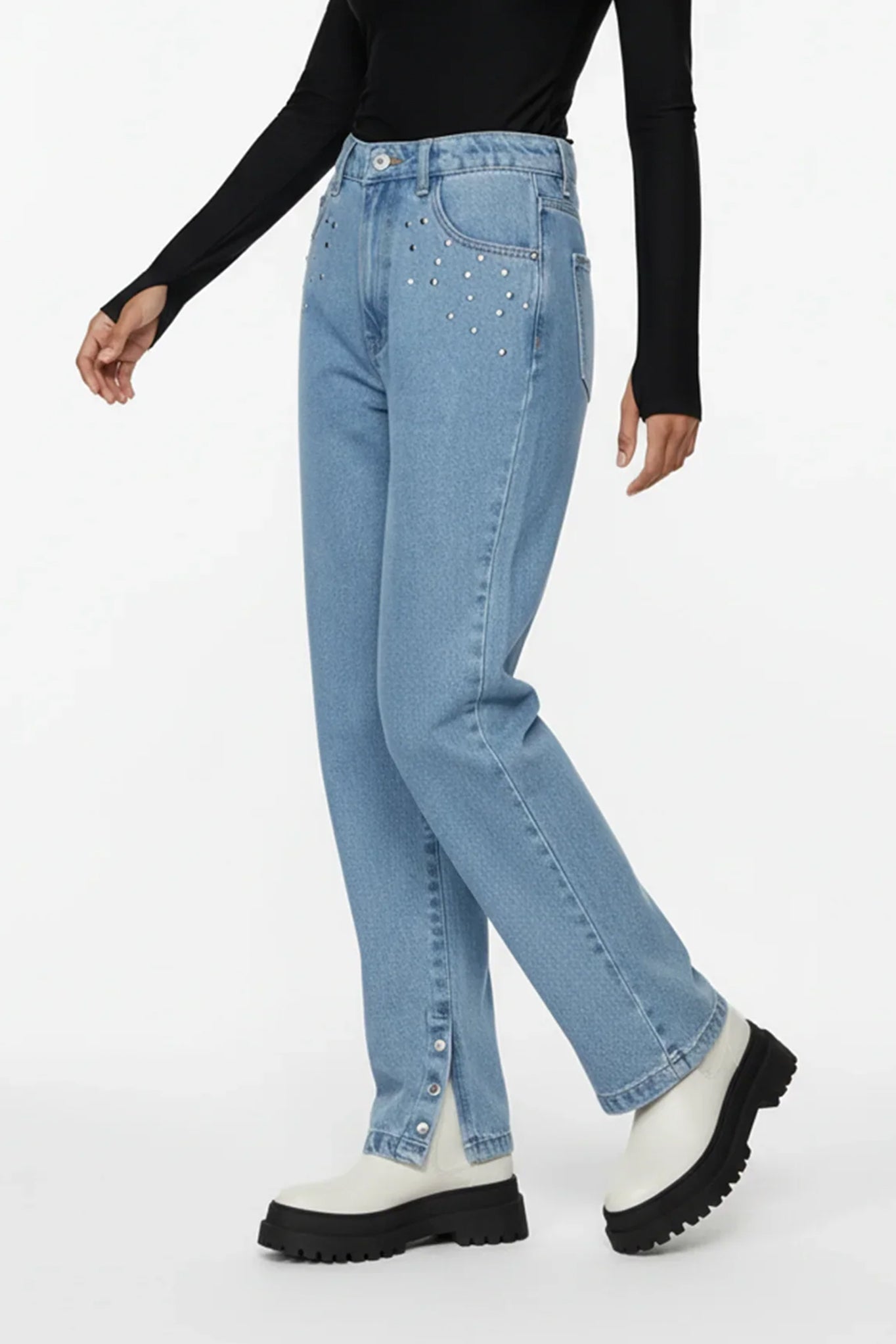 Person wearing light blue jeans and white platform boots on a white background