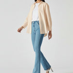 Side view of model walking to highlight the leg shape of light blue bootcut jeans