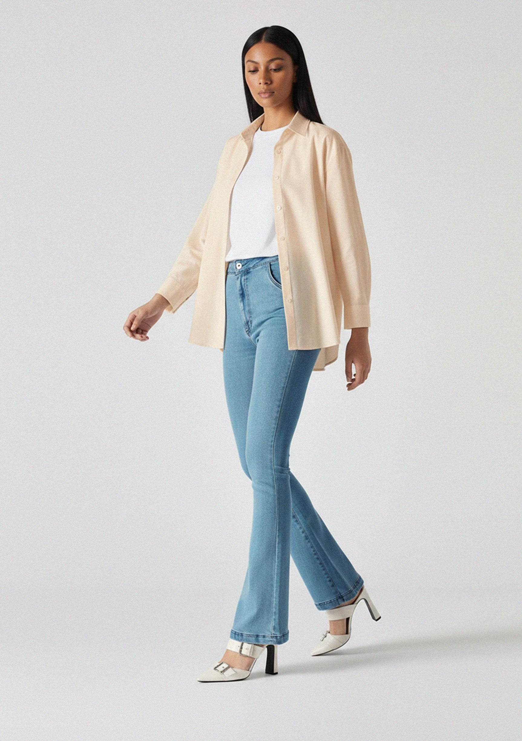 Side view of model walking to highlight the leg shape of light blue bootcut jeans
