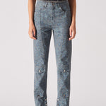 Person wearing light blue jeans with button details on a plain background