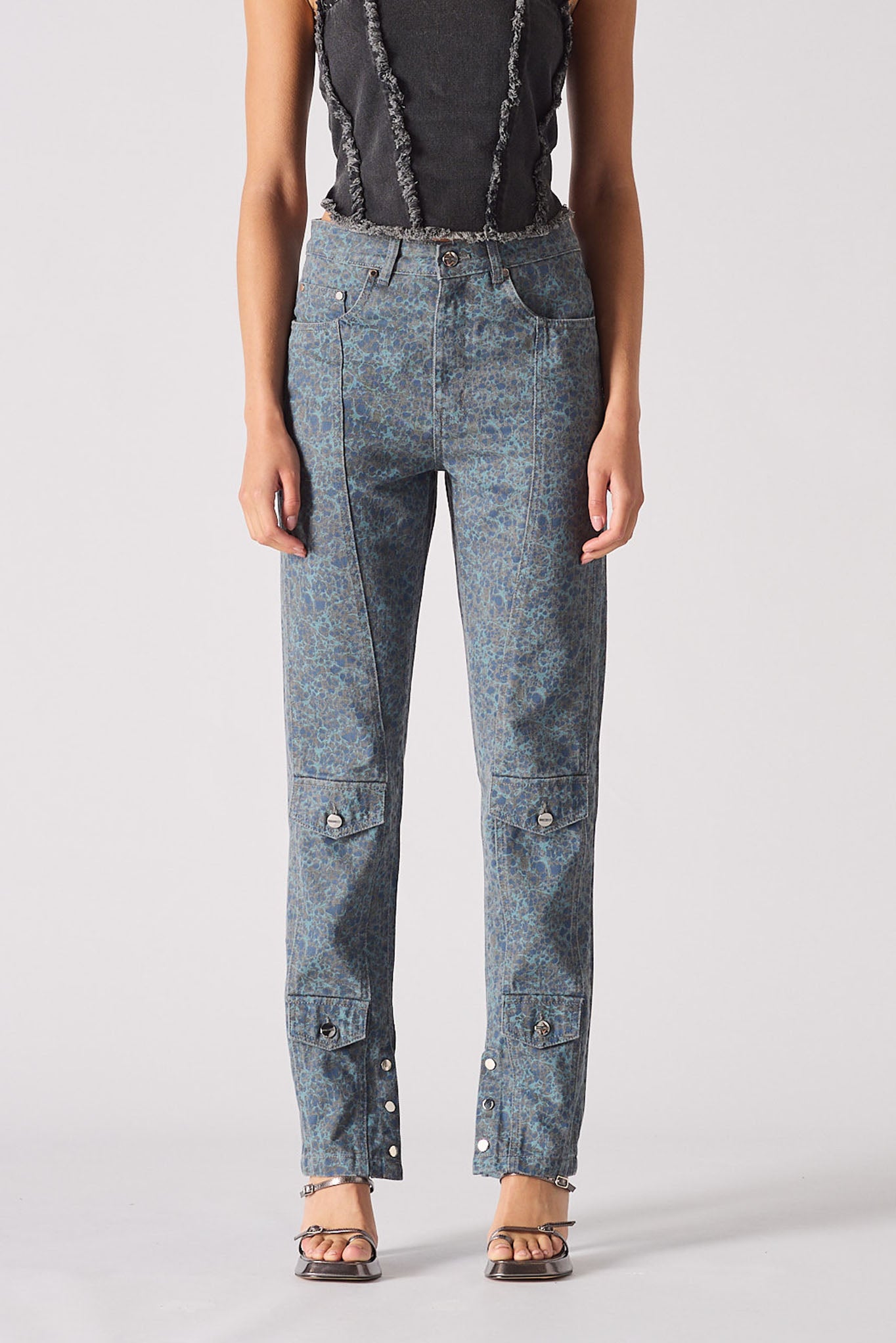 Person wearing light blue jeans with button details on a plain background