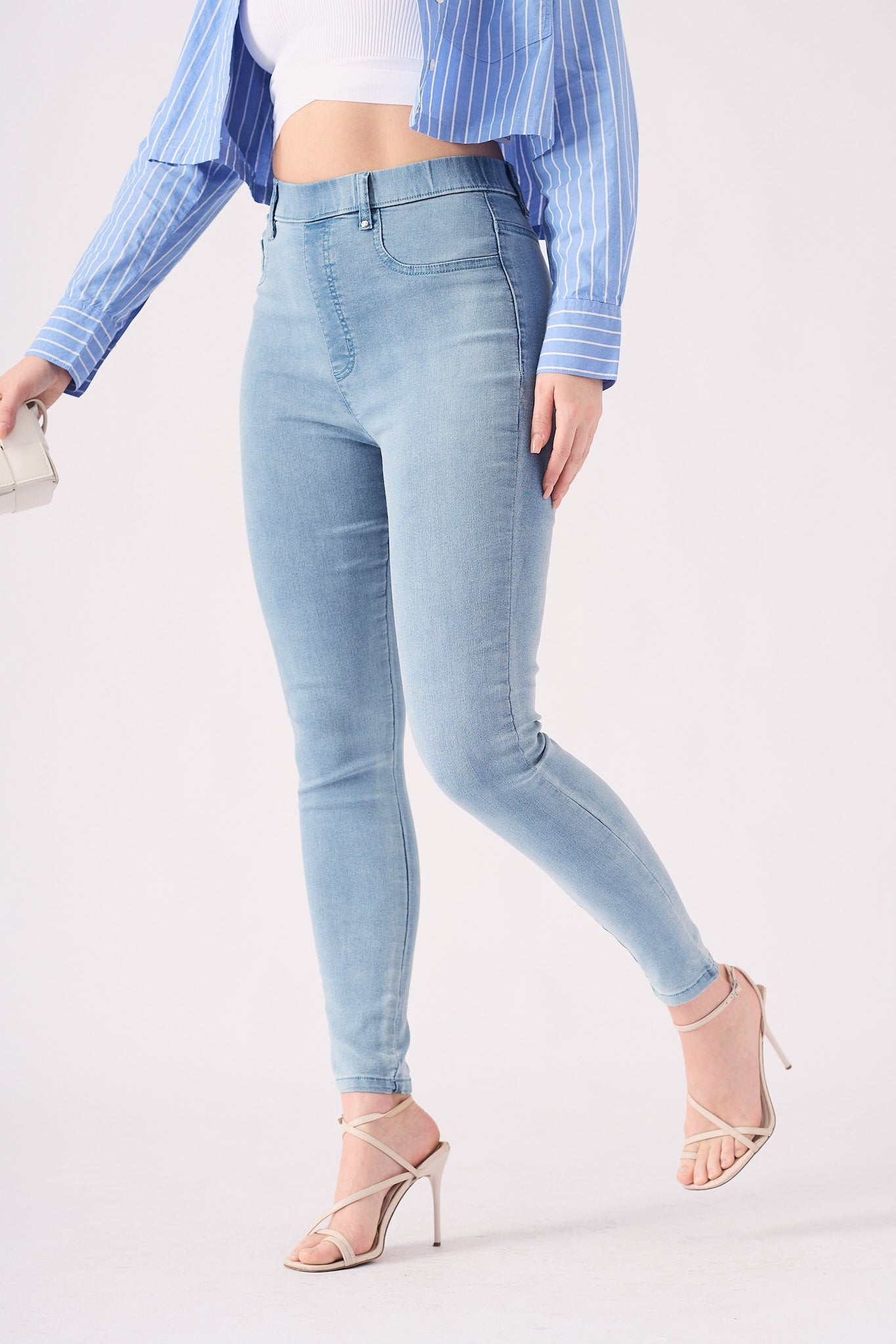 A model in a walking pose to demonstrate the flexibility and movement of the light blue jeggings.
