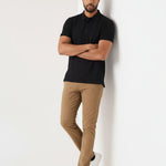 Model leaning against wall in men's light brown chinos