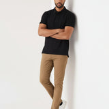 Model leaning against wall in men's light brown chinos