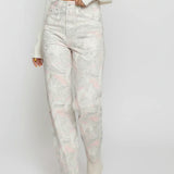 Person wearing light-colored floral jeans and a white top on a plain background