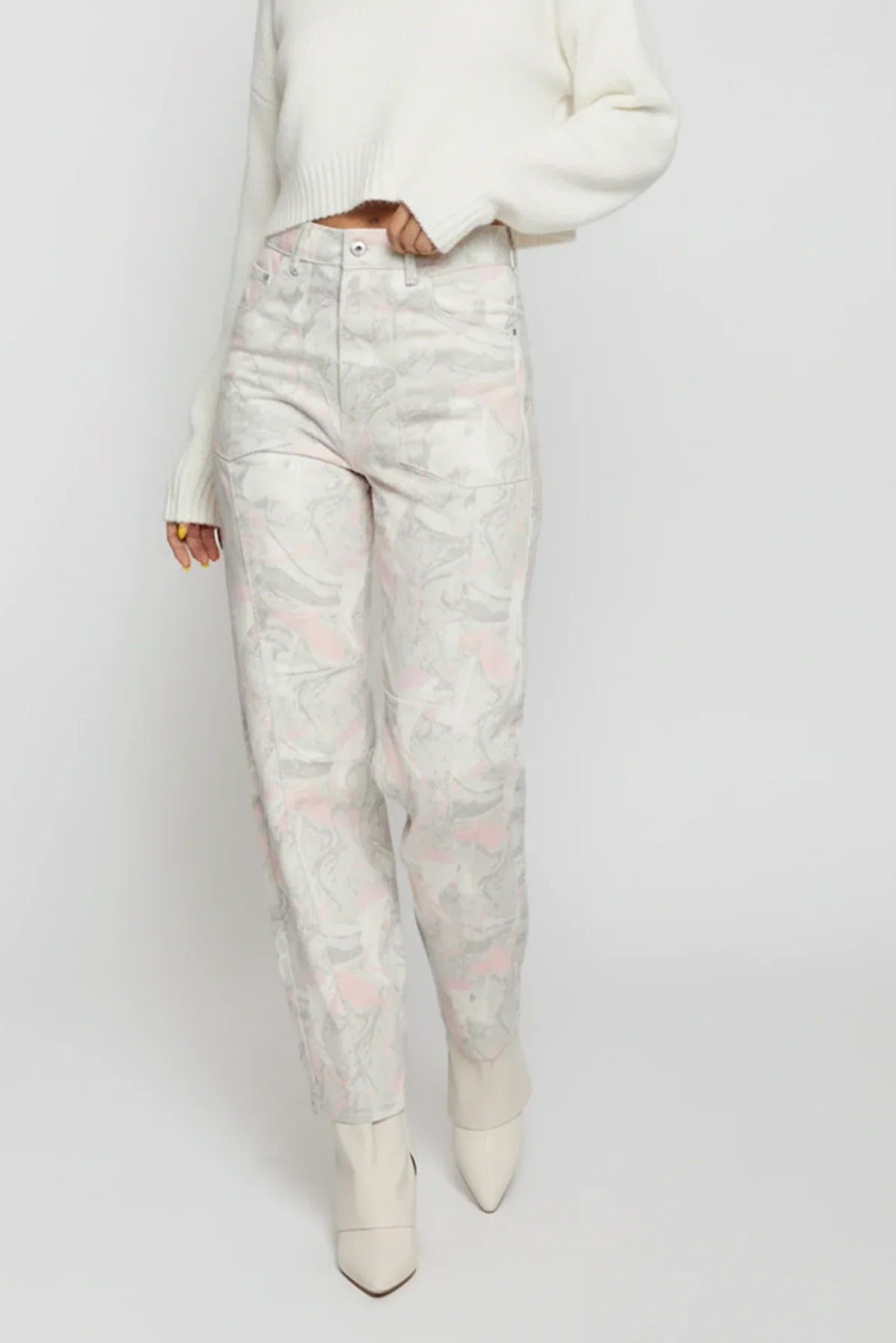 Person wearing light-colored floral jeans and a white top on a plain background