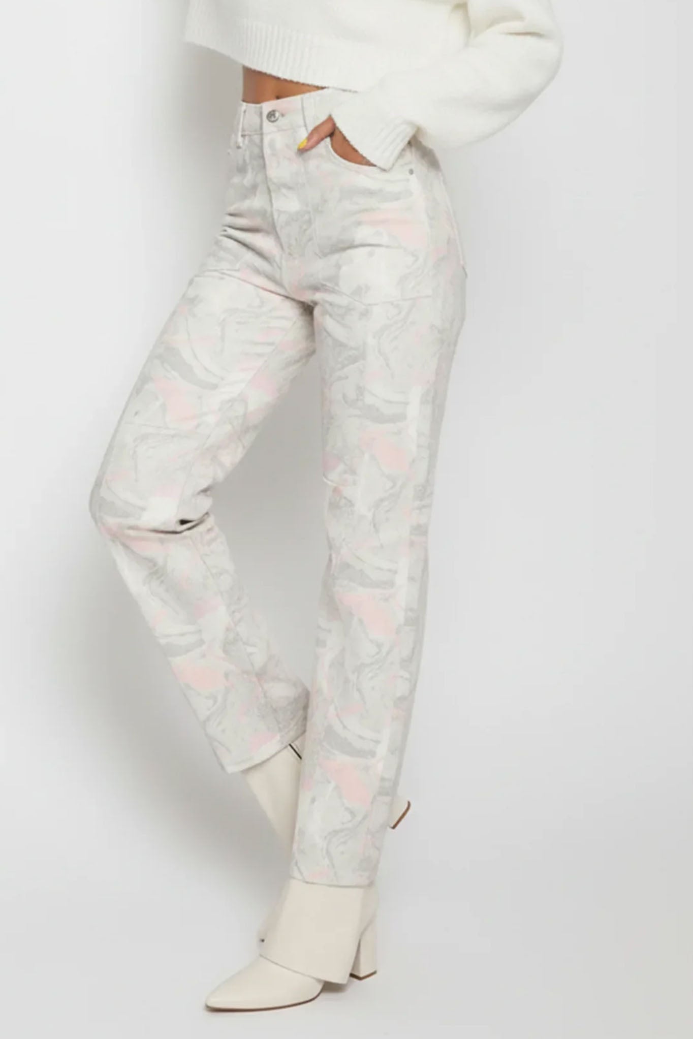 Person wearing light-colored jeans and a white top on a plain background