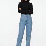 Model standing with arms crossed showcasing light denim straight leg pants featuring silver pocket studs.