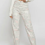 Model adjusting the waistband of light gray trippy print denim jeans, showing the high-rise fit.