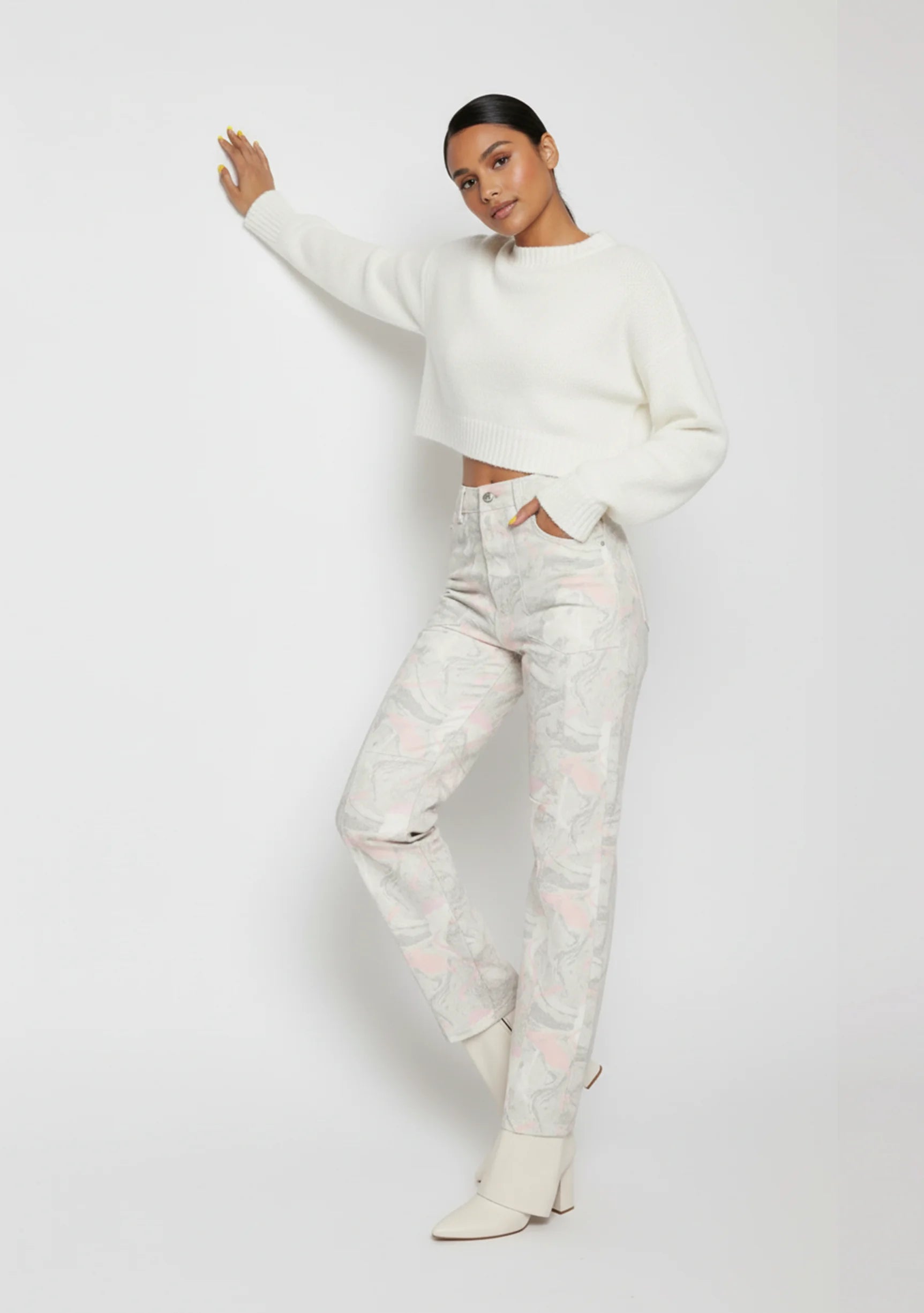 Close up front view of light grey psychedelic wash denim highlighting the angled pockets and snap button hem detail.