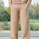 Close-up of the men's beige wide-leg joggers with embroidered logo detail