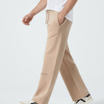 Side profile of a model walking in the Herman men's beige wide-leg joggers.