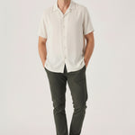 Handsome man styling mens chino pants olive green with hands resting in his pockets.