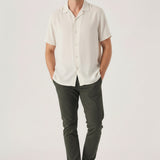 Handsome man styling mens chino pants olive green with hands resting in his pockets.