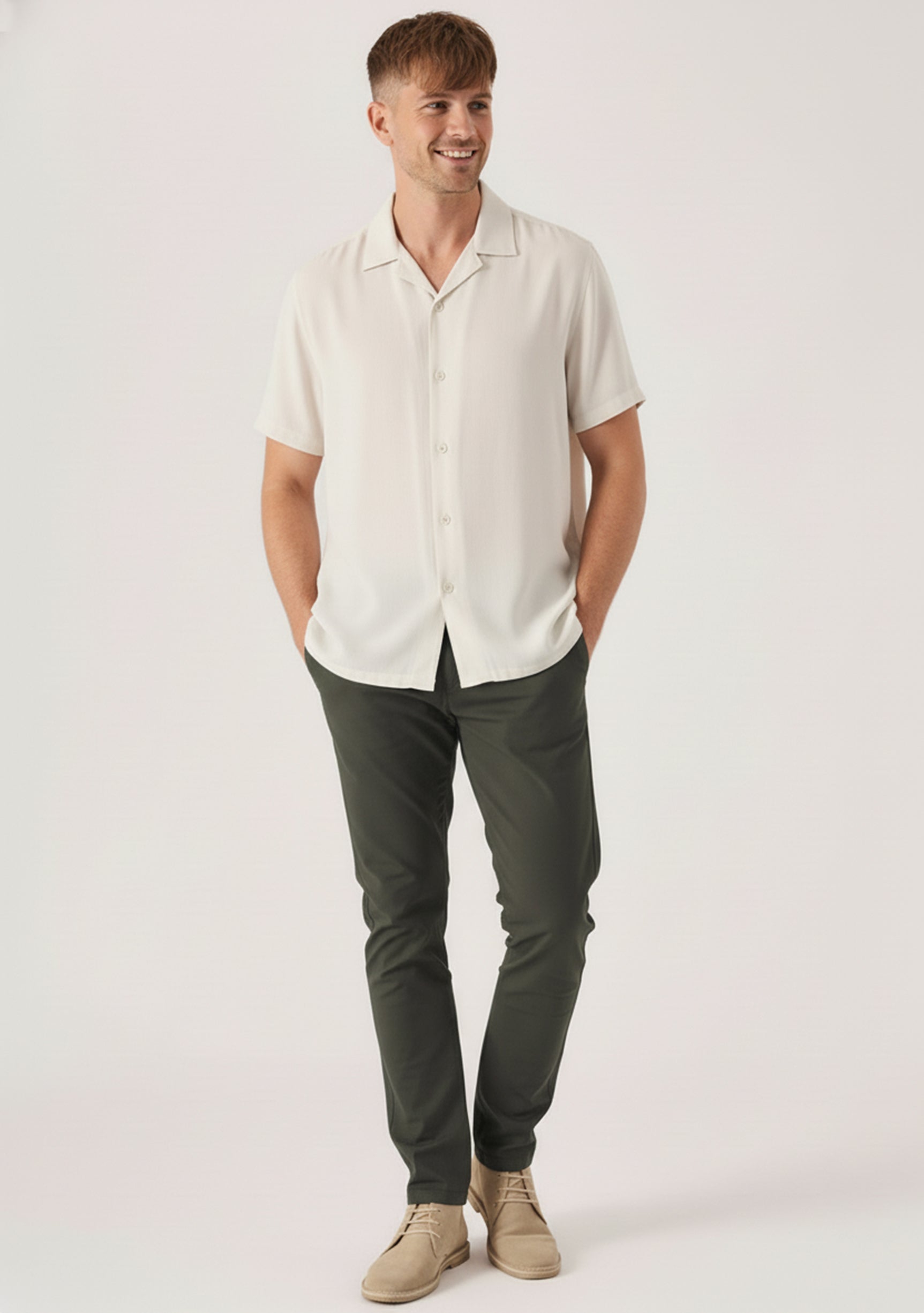 Handsome man styling mens chino pants olive green with hands resting in his pockets.