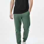 front view of man wearing dark green tapered joggers with white trainers