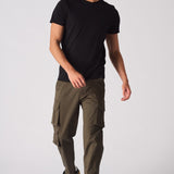 A man wearing slim fit green cotton cargo pants with a black t-shirt and trainers.