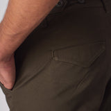 Detailed view of the front pocket and durable green cotton material of the cargo pants.
