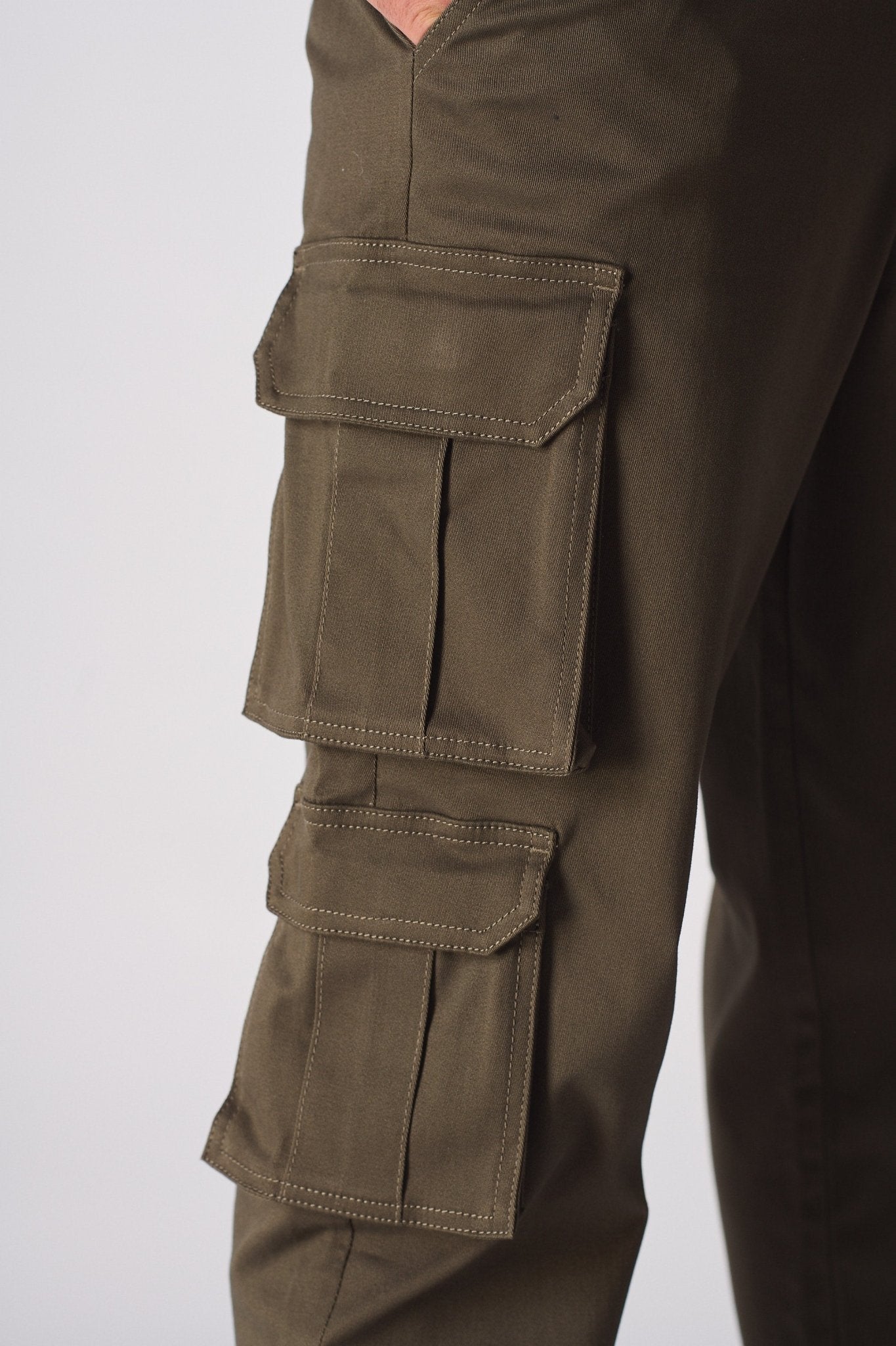 A side profile view of a model walking in green cotton cargo pants for men.