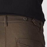 A man in a walking pose highlighting the flexible stretch fabric of the green cotton cargo pants.