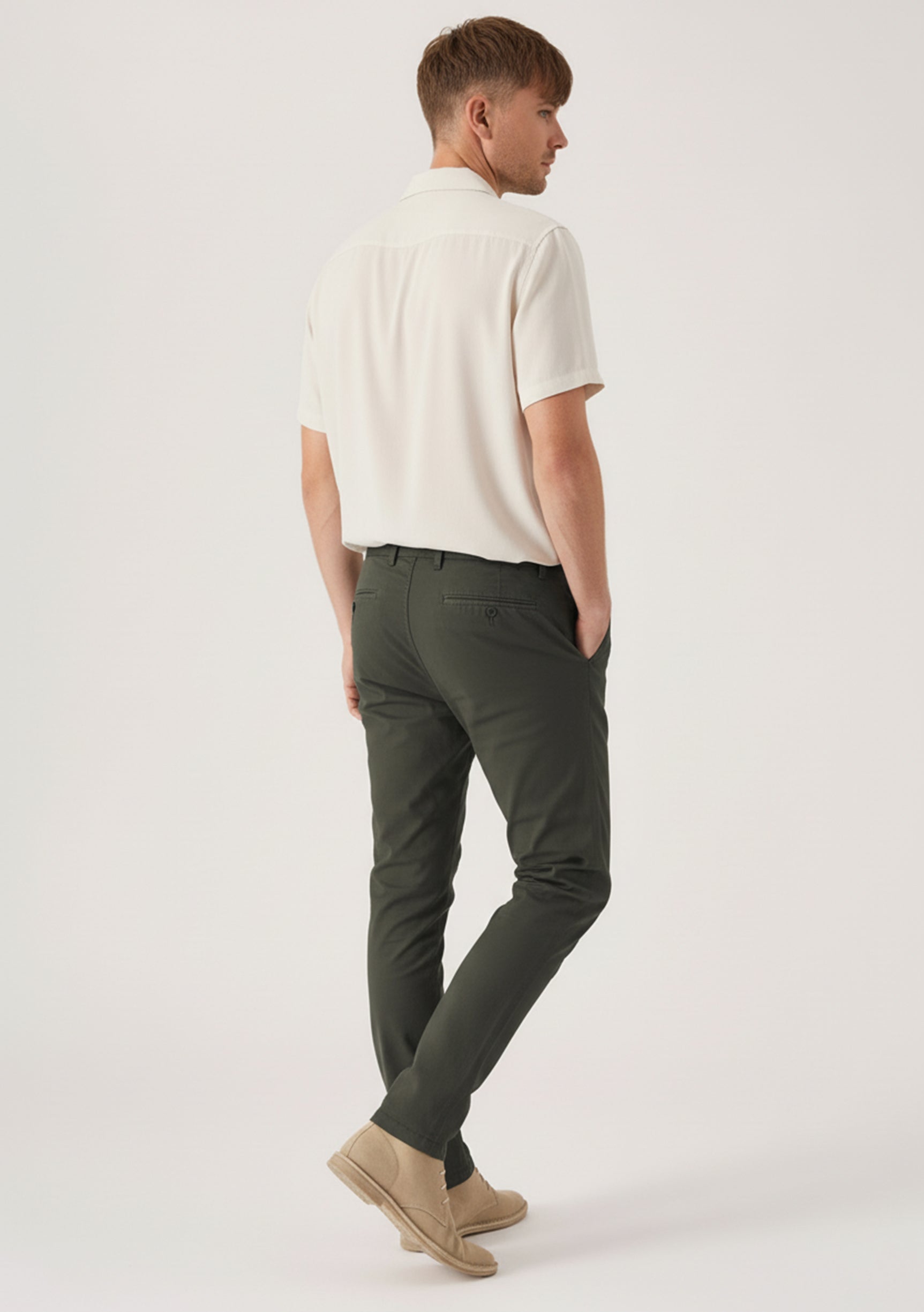 Back angled view of a model wearing comfortable mens olive green chinos by Jmojo.