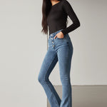Model with arms crossed wearing high-waisted mid blue bootcut jeans