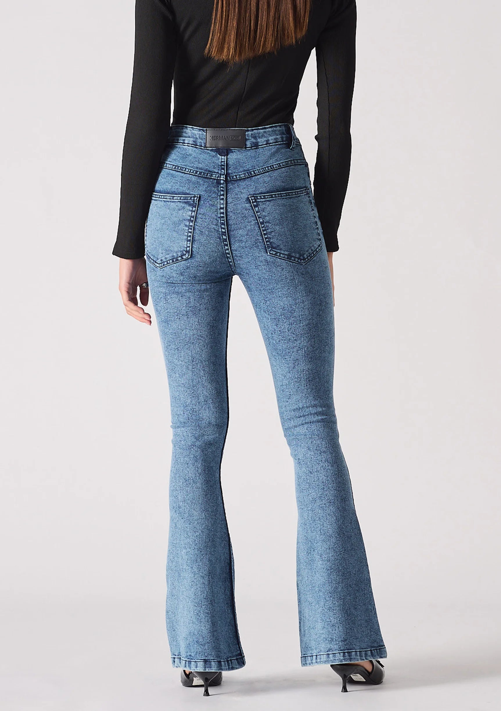Back view of women's mid blue bootcut jeans showing classic back patch pockets