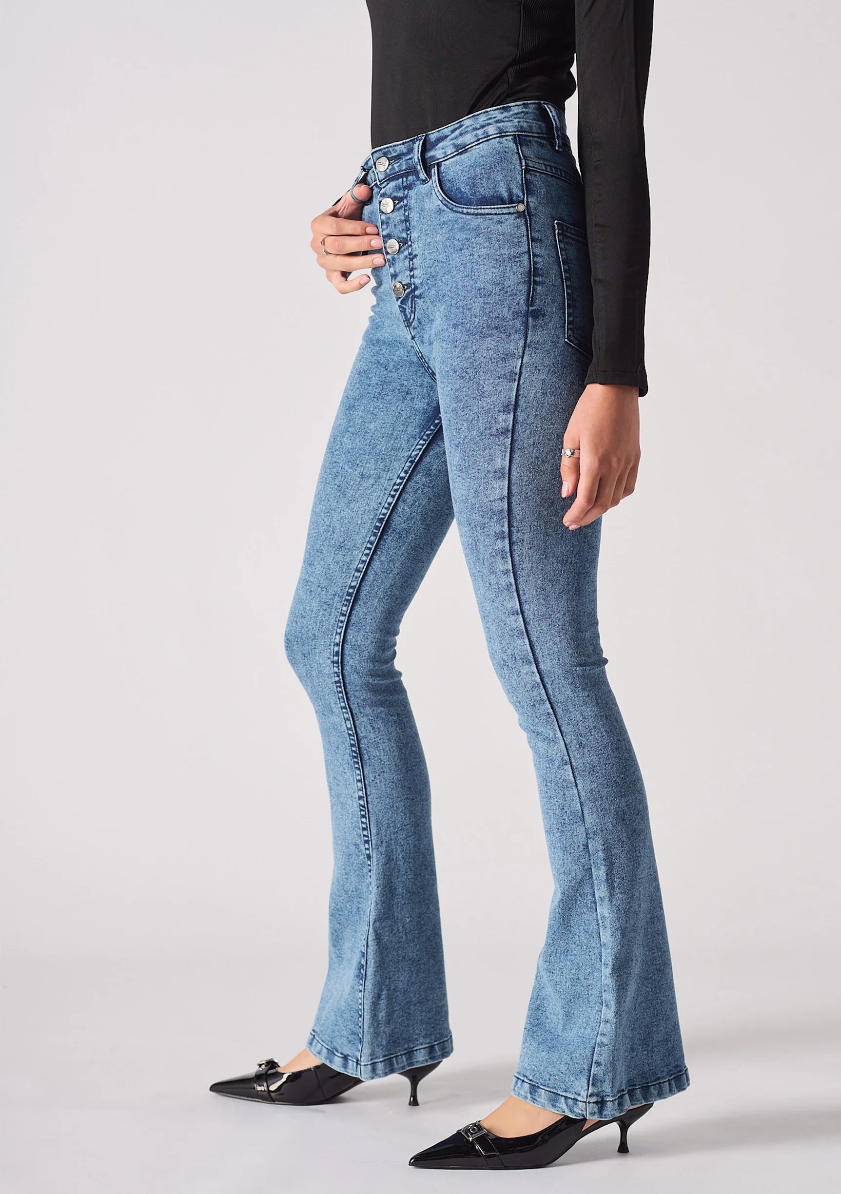 Angled side view of model wearing high-waisted mid blue bootcut jeans