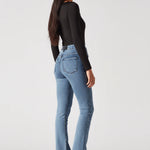 Full back view of model wearing form-fitting mid blue bootcut jeans