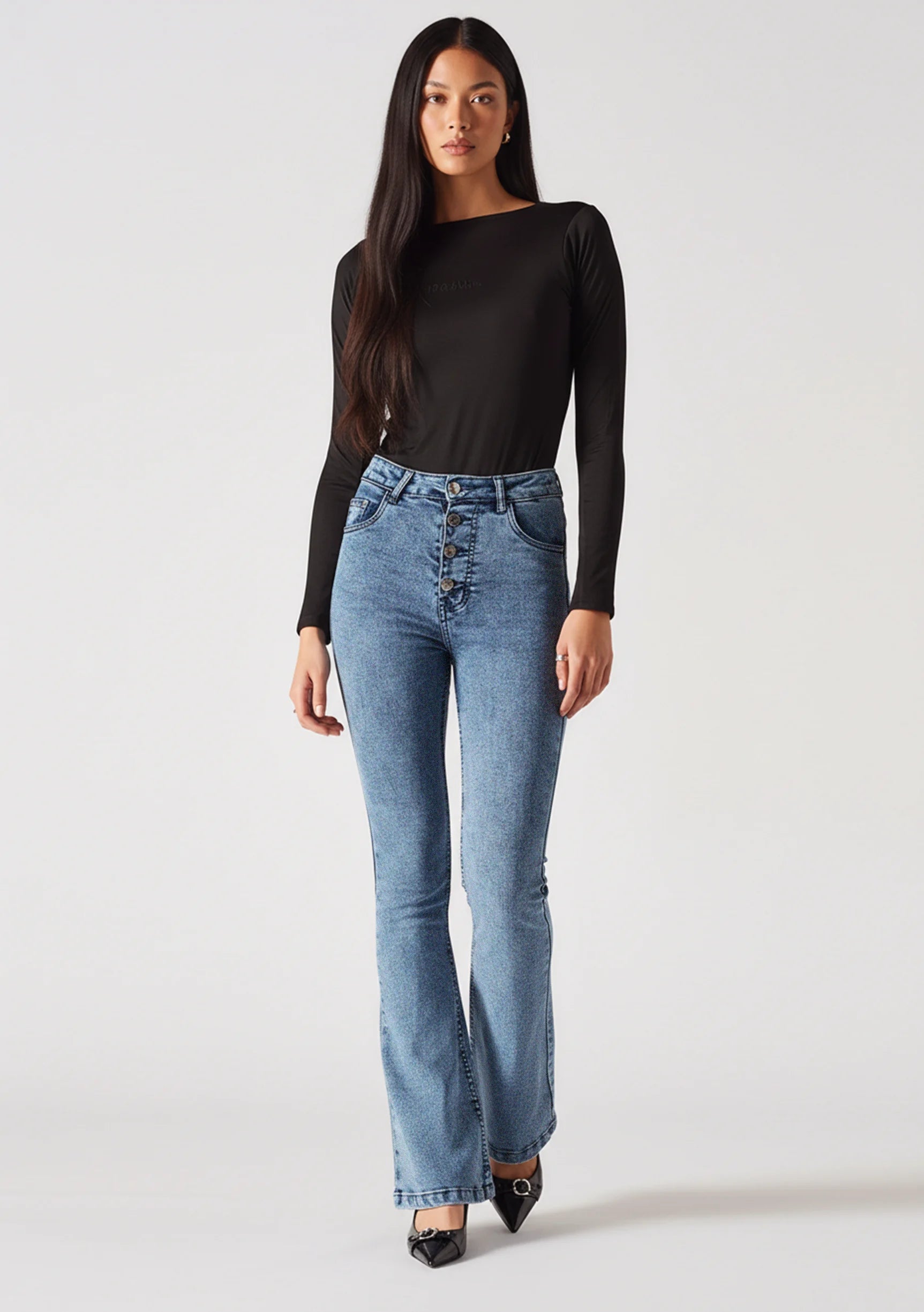 Angled front view showing the fit of mid blue exposed button fly jeans