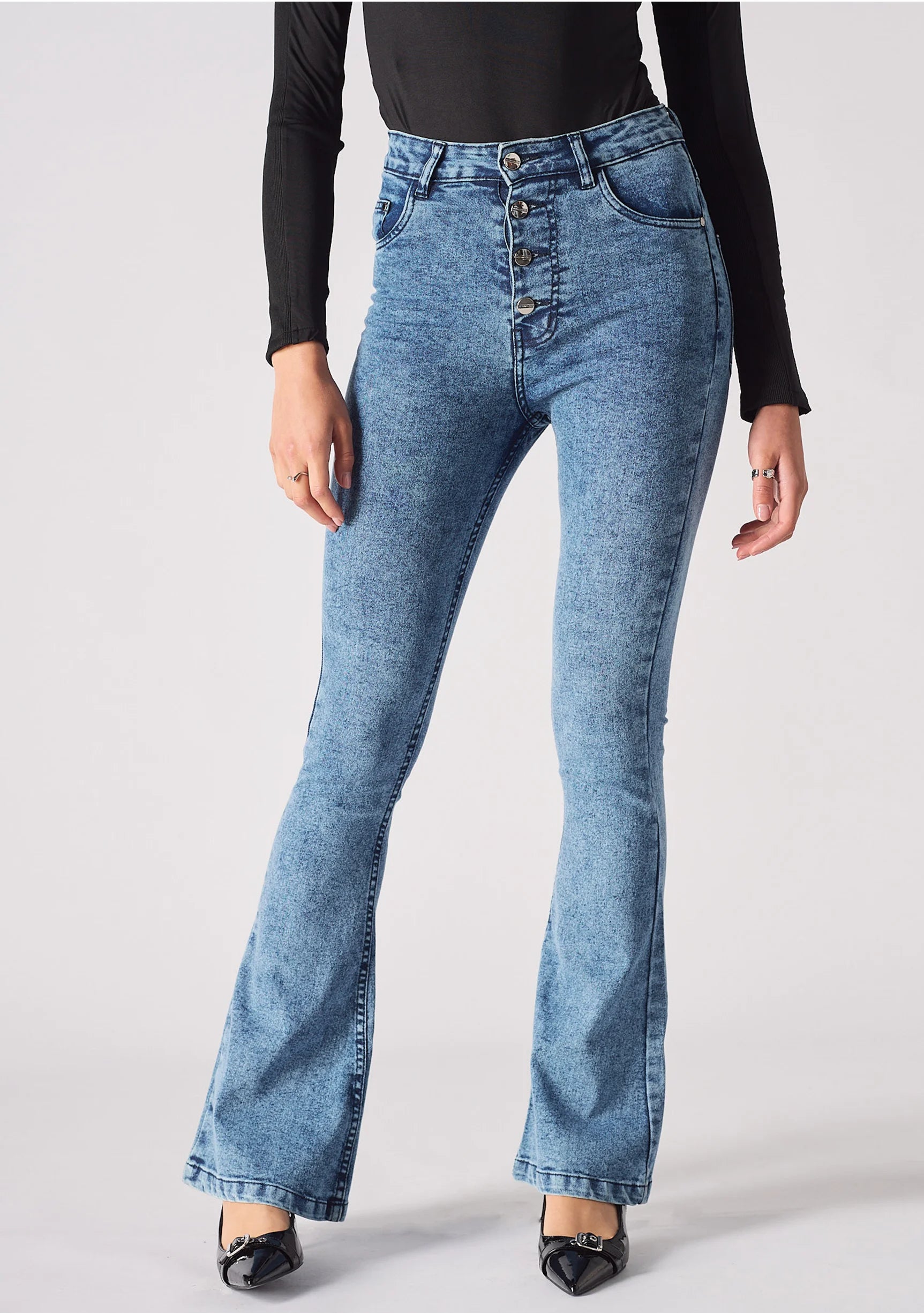Close up of the high waist, front pockets, and exposed metal button fly on mid blue denim
